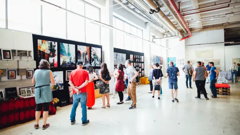 Besucher betrachten eine vielfältige Kunstausstellung in einem hellen, weitläufigen Galerieraum.