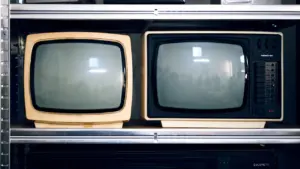 Zwei historische Fernsehgeräte in einem Regal als Zeugen des Alltags in der DDR.