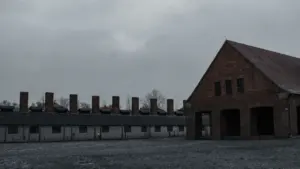 Historisches Backsteingebäude im ehemaligen Konzentrationslager Auschwitz-Birkenau unter einem bewölkten Himmel.
