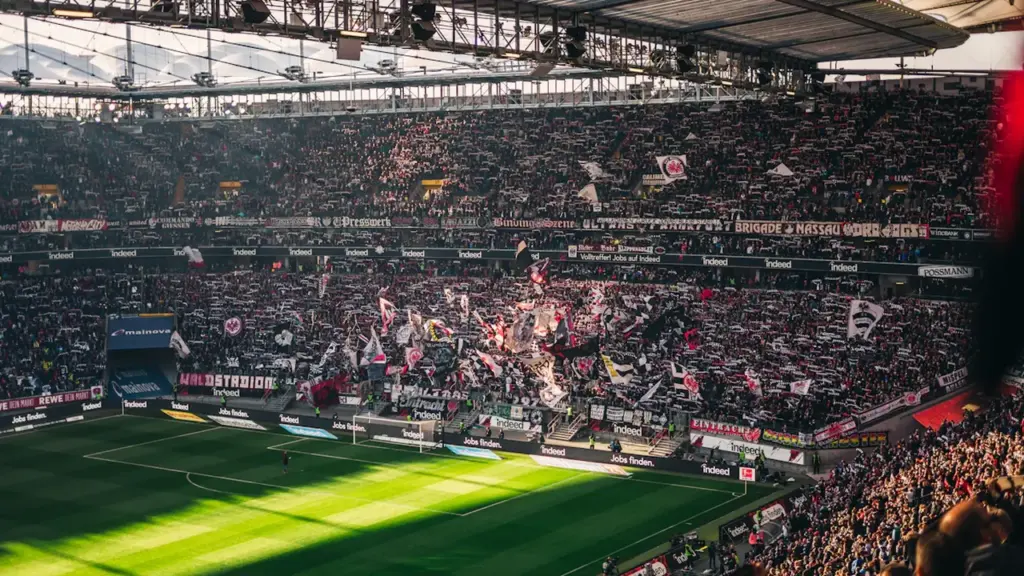 Weites Fußballstadion gefüllt mit zahlreichen Zuschauern während eines spannenden Spiels am Tag.