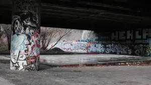 Eine von Graffiti verzierte Betonwand unter einer Brücke in einem Park.
