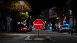 Ein beleuchtetes 'Einfahrt verboten'-Verkehrsschild bei Nacht an einer innerstädtischen Straße.