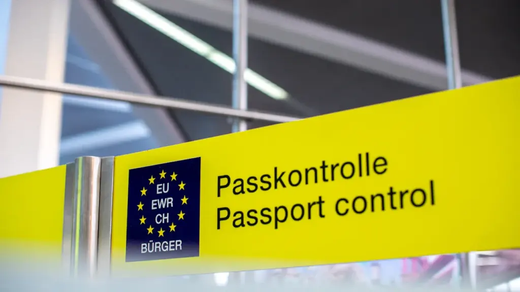 Ein gelbes Schild mit der Aufschrift Passkontrolle am Flughafen.