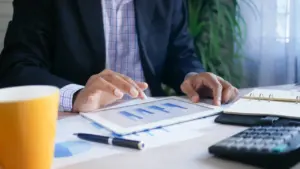 Geschäftsmann in Anzug arbeitet mit Tablet und Finanzstatistiken im Büro