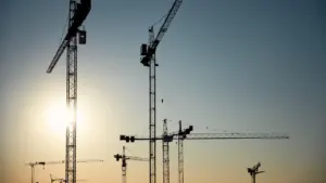 Mehrere Baukräne ragen vor einem klaren Himmel über einer Baustelle in Karlsruhe auf.
