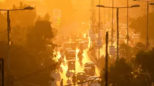 Dichte Stadtstraße mit Autos und Motorrädern in goldenem, staubigem Sonnenlicht bei Sonnenuntergang.