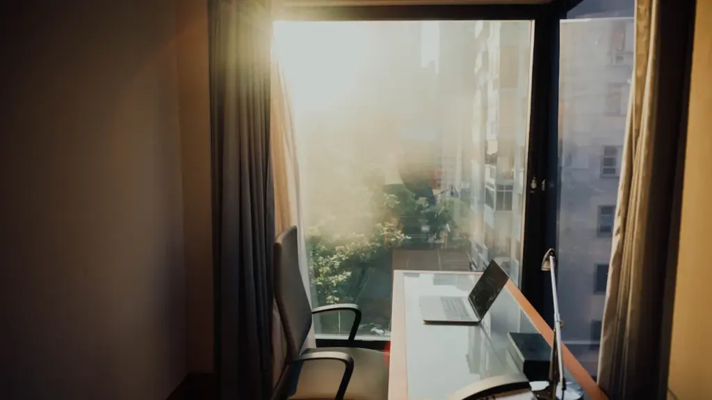 Ein heller, sonnendurchfluteter Homeoffice-Arbeitsplatz mit einem Laptop am Fenster.