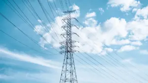 Strommast vor blauem Himmel mit weißen Wolken als Symbol für das deutsche Stromnetz