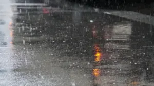 Regennasse Straße bei schlechtem Wetter mit Reflexion eines roten Ampelsignals