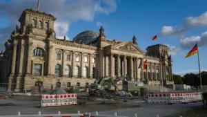 Das Berliner Reichstagsgebäude mit deutscher Flagge bei strahlend blauem Himmel.