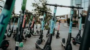 Mehrere abgestellte E-Scooter verschiedener Verleihfirmen auf einem städtischen Gehweg in Europa.