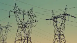 Große Stromübertragungsmasten gegen einen farbenfrohen Abendhimmel, Symbol für die deutsche Energiewende.