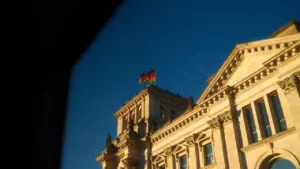 Das Reichstagsgebäude mit deutscher Flagge unter einem strahlend blauen Himmel in Berlin.