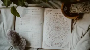 Ein offenes Horoskop-Buch auf einem weichen Laken mit einem dekorativen Kristall.