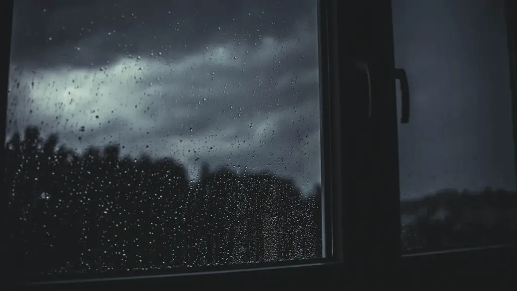 Regentropfen an einer Fensterscheibe vor einem verwaschenen Hintergrund in Köln bei Regenwetter.