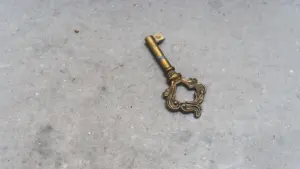 Ein alter goldener Skelettschlüssel liegt auf einem schlichten grauen Betonboden.
