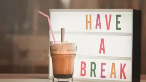 Ein Glas Eiskaffee steht neben einem leuchtenden Schild mit der Aufschrift Have a break.