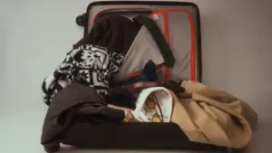 Ein offener, überquellender Koffer mit Kleidung als Symbol für die Reisevorbereitung oder Belastung.